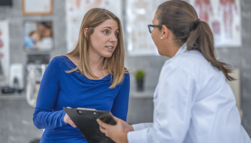 Besorgte Frau spricht mit ihrer Ärztin in einer medizinischen Einrichtung.