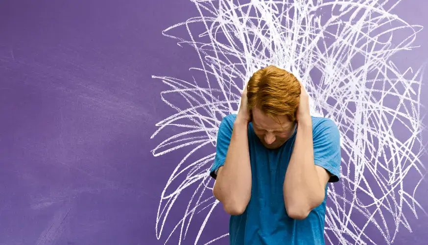 Eine Person in einem blauen Hemd hält sich die Ohren zu und neigt den Kopf. Hinter ihr sind weiße Kritzeleien auf lila Hintergrund zu sehen, die auf Stress oder Überforderung hindeuten.