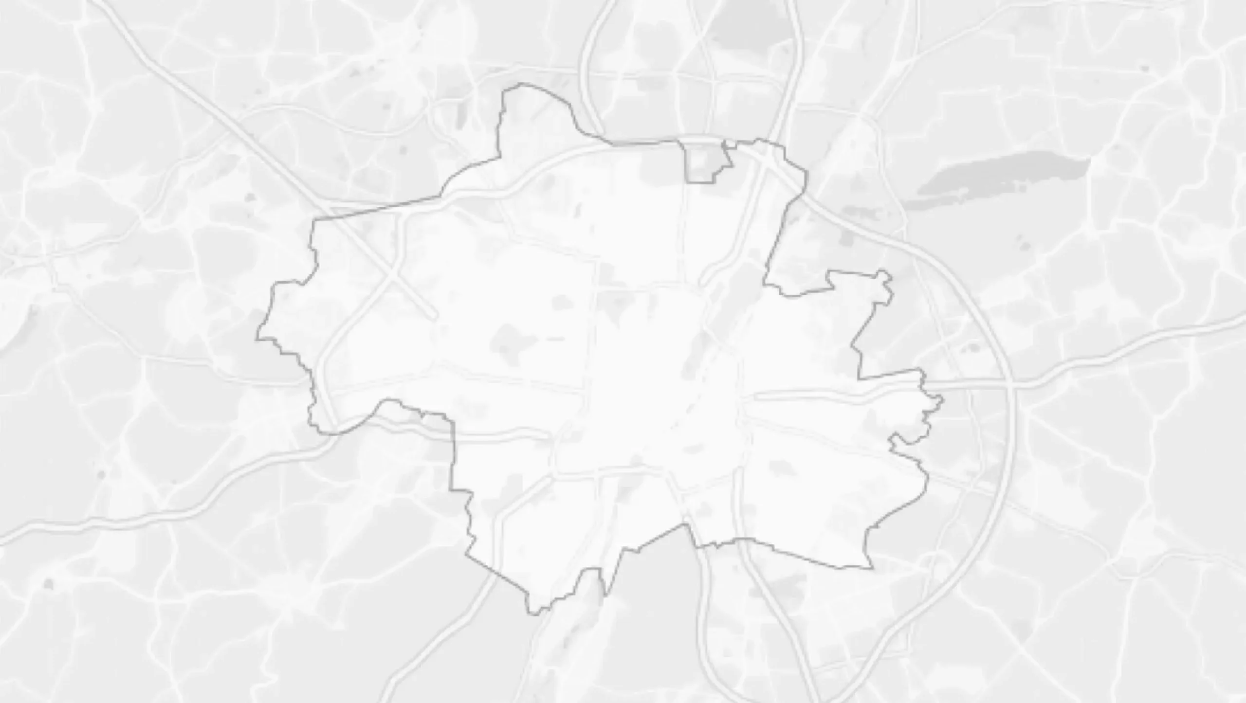 Eine Graustufenkarte, die die Grenzen einer Stadt oder Region zeigt, mit schwach sichtbaren Straßen und geografischen Merkmalen im Hintergrund. Der zentrale Bereich ist durch einen fetten schwarzen Rand hervorgehoben.